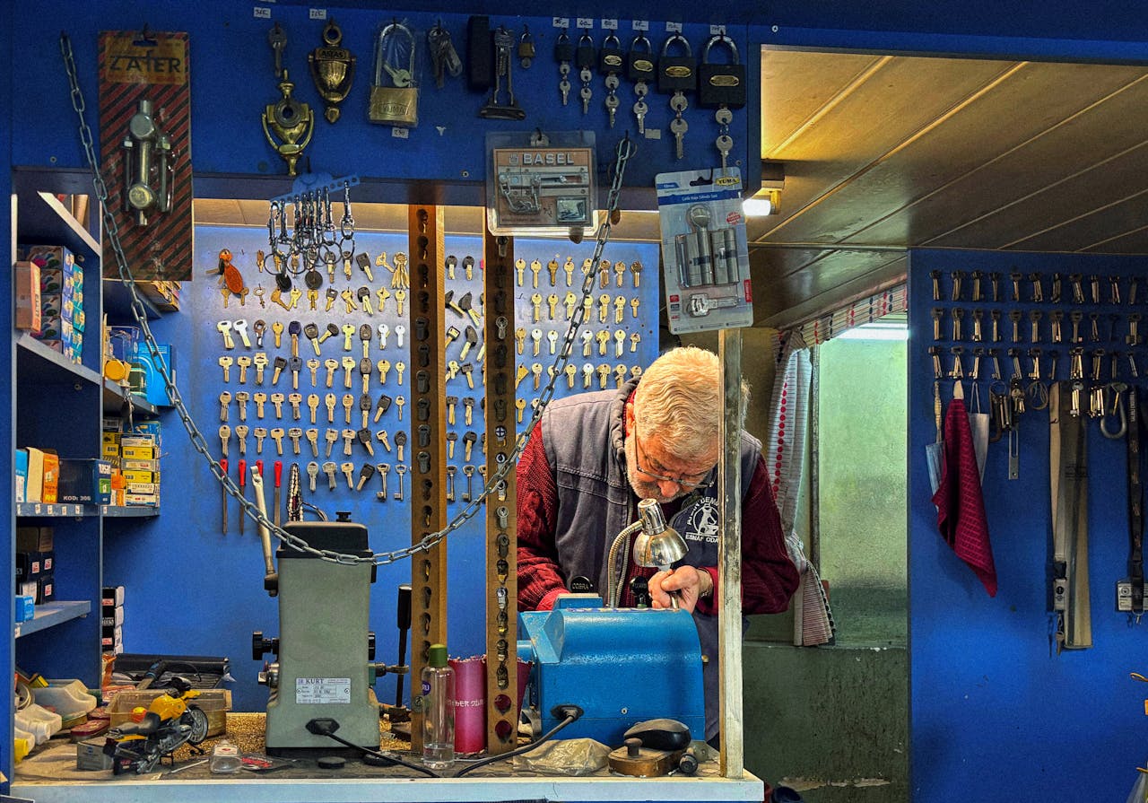 A senior locksmith crafts a key in his hardware shop filled with locks and keys.